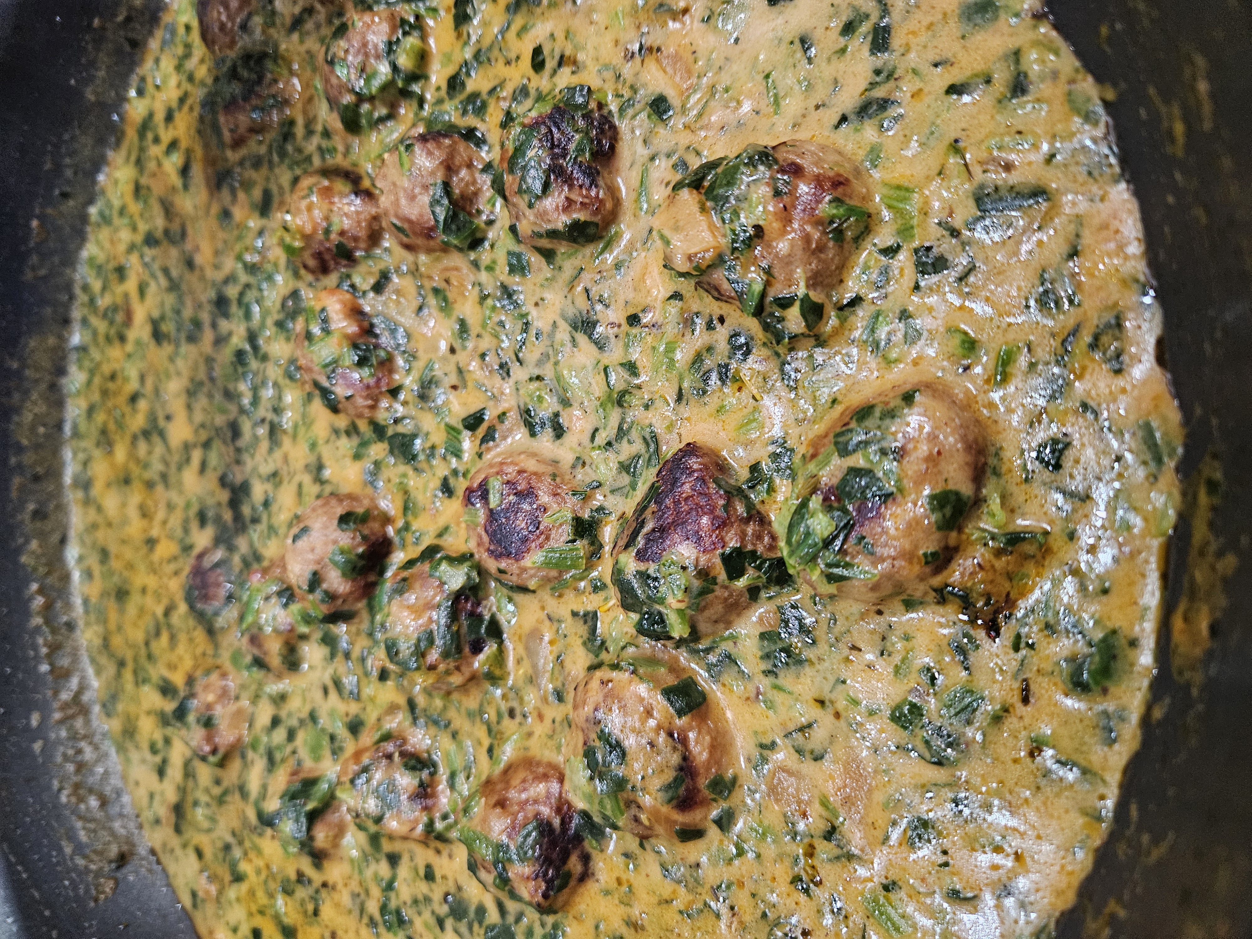 Spicy Pork Meatballs in a pan of spinach cream sauce