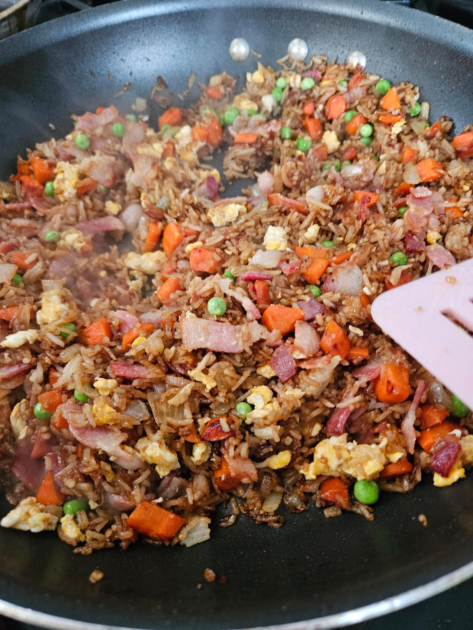 Image of stir-fried rice with carrots, peas, onions, bacon, and eggs.