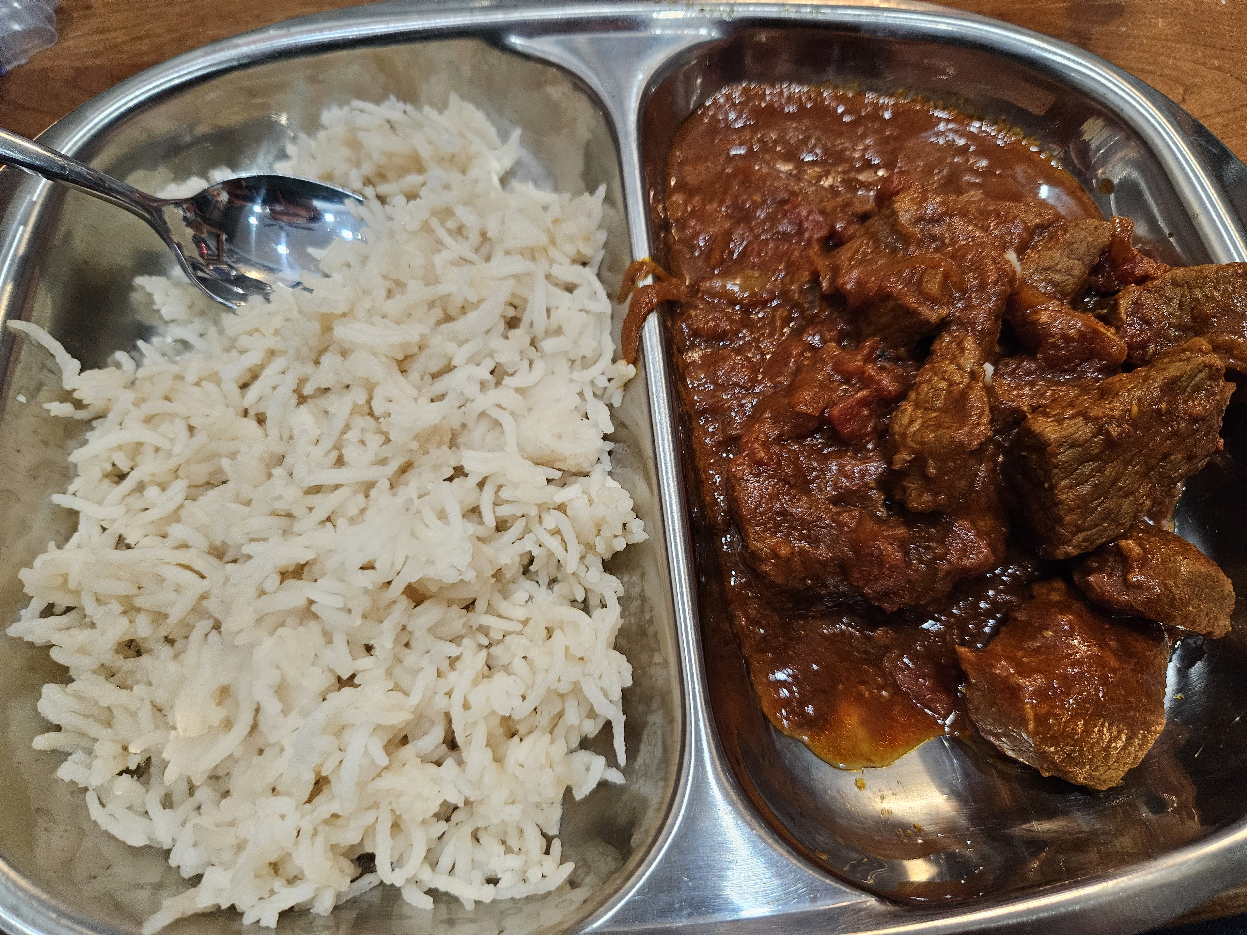 A metal tray with basmatti rice and lamb vindaloo